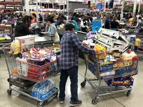 A Costco customer stands by his two shopping carts at a Costco store on March 13, 2020 in Richmond, California.