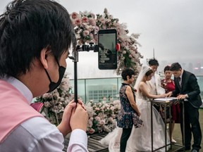A groomsman livestreams a wedding ceremony on March 29, 2020 in Hong Kong, China. Hong Kong government imposed new social distancing measures that limits public gatherings to four people, with some exemptions. (Getty Images)