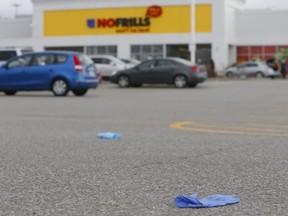 Latex gloves, tossed away by shoppers before getting into their vehicles, litter the parking lot at a No Frills grocery store on Island Rd., near Port Union Rd. and Hwy. 401, in Scarborough on Wednesday, March 25, 2020. (Chris Doucette/Toronto Sun/