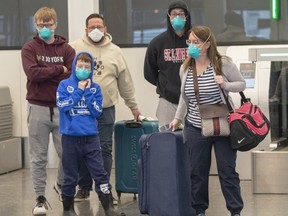 Travellers wear masks as they walk through Trudeau Airport on March 13, 2020. (The Canadian Press)