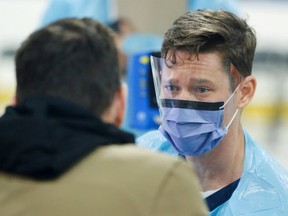 A medical worker assesses someone portraying the role of a patient as hospital staff prepare to receive people for coronavirus screening at a temporary assessment centre at the Brewer hockey arena in Ottawa on March 13, 2020. (Reuters)