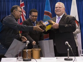 Ontario Premier Doug Ford, right, Chief Cornelius Wabasse, Webequie First Nation, left, and Chief Bruce Achneepineskum, Marten Falls First Nation, centre, give each other gifts after their signed agreement regarding the ring of fire in Northern Ontario at the Prospectors and Developers Association of Canada's annual convention in Toronto on Monday, March 2, 2020.