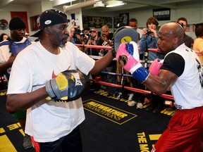 Boxer Floyd Mayweather Jr. (R) works out with his trainer and uncle Roger Mayweather at the Mayweather Boxing Club on April 22, 2014 in Las Vegas, Nevada.