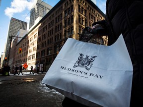 A woman holds a Hudson's Bay shopping bag in front of the Hudson's Bay Company (HBC) flagship department store in Toronto January 27, 2014. REUTERS/Mark Blinch/File Photo ORG XMIT: FW1