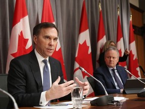 Canada's Finance Minister Bill Morneau (L) speaks during a news conference March 18, 2020 in Ottawa, Ontario, as Bank of Canada Governor Stephen Poloz looks on.