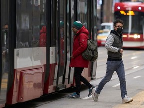 A man in a mask gets off a street car in downtown Toronto, Ontario on March 24, 2020.