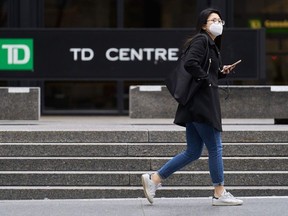 A woman in a mask walks in the financial district in Toronto, Ontario on March 24, 2020.