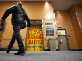 A visitor walks past a sign indicating to wash hands on the elevator doors at the Jewish General Hospital in Montreal, Quebec, on Monday