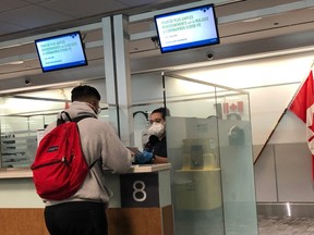 A Canada Border Services Agency (CBSA) officer wears a protective face mask amid coronavirus fears as she checks passports for those arriving at Toronto Pearson International Airport in Toronto, Canada, March 15, 2020.