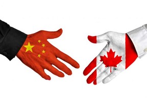 Diplomatic handshake between leaders from China and Canada with flag-painted hands.