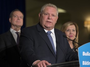 Premier Doug Ford (C) answers a question as Christine Elliott, (R) Deputy Premier and Minister of Health and Peter Bethlenfalvy, President of the Treasury Board (L) listen. A team of provincial ministers were available for a media conference Thursday morning at the Chateau Laurier.    Photo by Wayne Cuddington / Postmedia