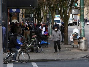 Residents of the Downtown Eastside gather to collect their social assistance cheques, as the number of coronavirus disease (COVID-19) cases continues to grow in Vancouver, British Columbia, Canada March 25, 2020.