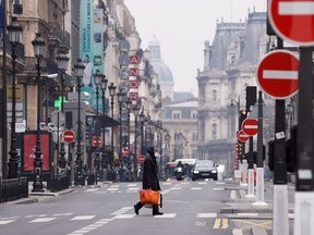 A man wearing a protective face mask crosses the deserted Rue de Rivoli in Paris as a lockdown is imposed to slow the rate of the coronavirus disease (COVID-19) in France, March 18, 2020.