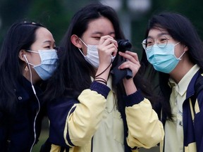 High school students wear protective face masks to protect themselves from coronavirus disease (COVID-19) while taking photos of the flag rising ceremony at Chiang Kai Shek Memorial Hall in Taipei, Taiwan, March 11, 2020.