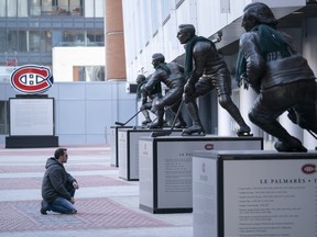 Keith Hynes reads the biography of his hero, Montreal Canadiens star Jean Beliveau, outside the Bell Centre in Montreal on Thursday, March 12, 2020. (THE CANADIAN PRESS/Paul Chiasson)