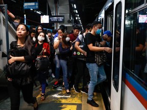 Commuters wearing protective face masks board a train in Manila, Philippines on Wednesday.