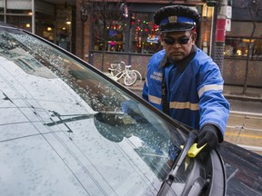 A parking enforcement officer places a ticket on a car on King St E in Toronto, Ont.  on Monday December 21, 2015. Ernest Doroszuk/Toronto Sun/Postmedia Network