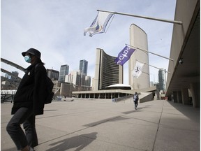 A small group of pedestrians pass through Nathan Phillips Square in front of Toronto City Hall on March 16, 2020.