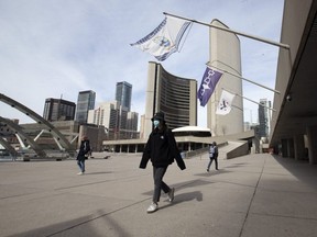 Pedestrians pass through Nathan Phillips Square in front of Toronto City Hall on March 16, 2020. The city recently created a snitch line for residents to report others who are breaking lockdown rules.