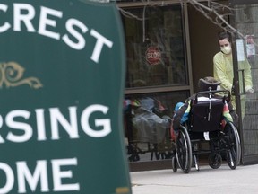 A staff member wearing personal protective equipment helps a patient back into Pinecrest Nursing Home in Bobcaygeon,  Ont. on Saturday. Two of the home's residents are dead in one of Ontario's largest COVID-19 outbreaks thus far.  14 health care workers have also tested positive, and 35 more patients are experiencing symptoms.