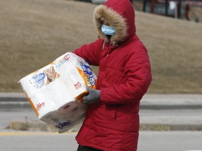 A woman wearing a mask and carrying toilet paper leaves the Pickering Town Centre on Wednesday March 18, 2020. Veronica Henri/Toronto Sun