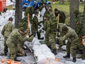 Members of the Canadian Armed Forces build a wall of sandbags to protect property against flood water in Ottawa on May 1, 2019.