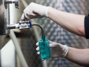 Distiller Phil Miller pours hand sanitizers at Spirit of York distillery in Toronto on March 19, 2020. - The company has started to make hand sanitizers since supplies has been running short due to COVID-19. (Photo by Lars Hagberg / AFP)