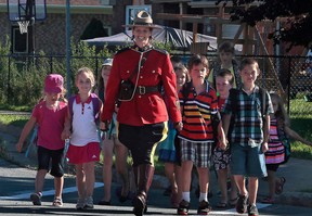 RCMP Const. Heidi Stevenson, who was shot and killed by a gunman April 19, 2020, walks children across a street in a September 2015 photograph from the RCMP in Nova Scotia’s Facebook site.