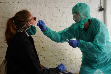 BERLIN, GERMANY - APRIL 08: Doctor Beate Krupka, dressed in a protective suit and mask, takes a throat swab from a young woman to test her for Covid-19 in a garage behind Krupka's practice during the coronavirus crisis on April 08, 2020 in Berlin, Germany. Krupka and her colleagues are using the garage to take samples from possible Covid-19 patients in order to avoid having them come into the practice and possibly contaminate it with the coronavirus. The city of Berlin has confirmed approximately 4,000 Covid-19 infections. Krupka said the number of people testing positive from her samples has been declining recently. Germany has over 100,000 confirmed cases of infection and over 1,800 people have died.  (Photo by Sean Gallup/Getty Images)