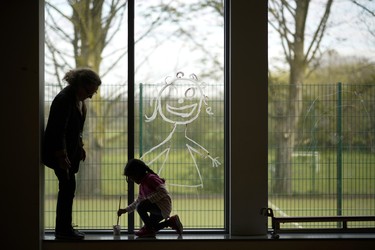ALTRINCHAM, ENGLAND - APRIL 08:  A young girl paints a picture of herself on the school window as children of key workers take part in school activities at Oldfield Brow Primary School on April 08, 2020 in Altrincham, England. The government announced the closure of UK schools from March 20 except for the children of key workers, such as NHS staff, and vulnerable pupils, such as those looked after by local authorities. The prime minister has said schools will remain closed "until further notice," and many speculate they may not reopen until next term. (Photo by Christopher Furlong/Getty Images)