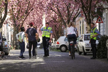 BONN, GERMANY - APRIL 08:  Security staff of the City of Bonn gives security advices to pedestrians in the streets of the blooming cherry blossom and cherry blossom trees at the historic district (Altstadt) during the coronavirus crisis on April 08, 2020 in Bonn, Germany. The City of Bonn blocks the popular streets to prevent large crowds.  The number of confirmed coronavirus cases in Germany has surpassed 100,000 and the number of deaths continues to rise. While public support for the measures imposed by authorities to limit public life in an effort to slow the spread of virus remains strong, people are wondering how long the measures will last, especially as the economic impact of the disruptions becomes more acute. (Photo by Andreas Rentz/Getty Images)