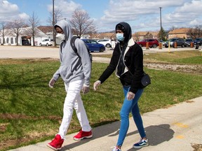 Two people walk by the Etobicoke General Hospital drive-thru COVID-19 assessment centre on April 9, 2020. (Reuters)