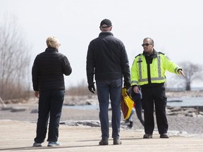 A bylaw officers looks  for people who refuse to abide by new social-distancing directives at Woodbine Beach, on Saturday April 11, 2020.