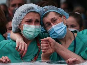 Health workers react during an April 13, 2020  tribute for a co-worker who died of COVID-19 at the Severo Ochoa Hospital in Leganes, Spain. (Reuters)