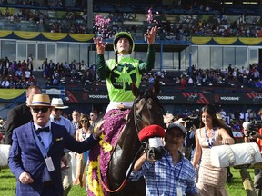 Jockey Flavien Prat, on top of One Bad Boy, throws flower petals in the air after winning the 160th Queen's Plate at Woodbine Racetrack, in Toronto on Saturday, June 29, 2019. THE CANADIAN PRESS/Frank Gunn