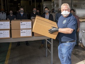 Ontario Premier Doug Ford loads ASTM Level 3 masks made by The Woodbridge Group in Woodbridge on Tuesday, April 7, 2020. THE CANADIAN PRESS/Frank Gunn