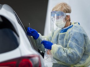 A health-care worker does testing at a drive-thru COVID-19 assessment centre at the Etobicoke General Hospital in Toronto on Tuesday, April 21, 2020.