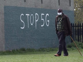 A man wearing a face mask during an outbreak of coronavirus disease walks past a graffiti that reads "STOP 5G" in London April 8, 2020. (REUTERS/Russell Boyce)