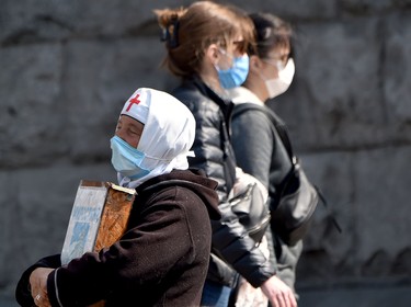 An elderly woman wearing a face mask, amid concerns over the spread of the novel coronavirus COVID-19, collects donations for her church in the center of the Ukrainian capital of Kiev on April 8, 2020. (Photo by Sergei SUPINSKY / AFP) (Photo by SERGEI SUPINSKY/AFP via Getty Images)