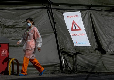 A healthcare worker walks past a sign reading "Attention, COVID Zone" attached to a big tent housing a field hospital outside the Gregorio Maranon Hospital in Madrid on April 8, 2020. - Spain recorded today a second successive daily rise in coronavirus-related deaths with 757 fatalities, lifting the total toll in Europe's second-hardest-hit country after Italy by 5.5 percent to 14,555. The number of new infections rose by 4.4 percent to 146,690, the health ministry said, as Spain has ramped up its testing for the disease. (Photo by OSCAR DEL POZO / AFP) (Photo by OSCAR DEL POZO/AFP via Getty Images)