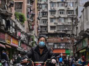 A man wearing a face mask ride a scooter on a street in Wuhan, China's central Hubei province on April 14, 2020. (Photo by HECTOR RETAMAL/AFP via Getty Images)
