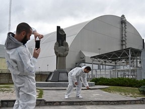 Tourists take pictures outside the New Safe Confinement (NSC), a metal dome encasing the destroyed reactor, at the closed Chernobyl nuclear plant, in Ukraine, on Aug. 15, 2019.