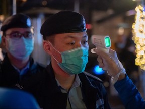 A police officer getting his body temperature measured by a bouncer as he enters a bar on March 29, 2020 in Hong Kong, China. (Anthony Kwan/Getty Images)