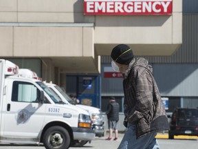 A man wears a protective face mask as he walks past the emergency department of the Royal Columbian Hospital in New Westminster, B.C.