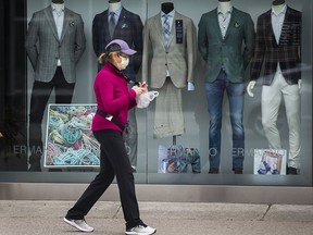 A masked pedestrian walks past a storefront along Yonge St., north of Sheppard Ave. in Toronto on Friday April 3, 2020.