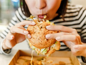 Woman eating a hamburger in modern fastfood cafe, lunch concept
