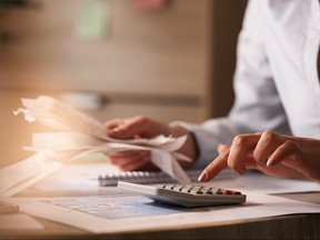 Close up of businesswoman using calculator while going through financial bills.