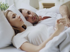 A couple with relationship problems having emotional conversation while lying in bed.