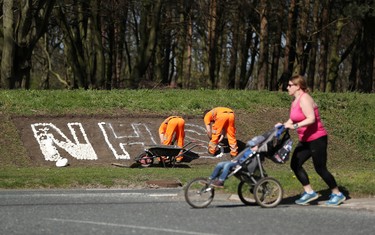 A woman pushes a pram as workers lay stones in support of the NHS on a roundabout in Durham, as the spread of the coronavirus disease (COVID-19) continues, Durham, Britain, April 8, 2020. REUTERS/Lee Smith ORG XMIT: AI