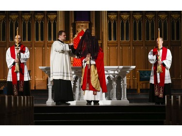 Roman Catholic Cardinal Thomas Colllins performs the Veneration of the Cross with the help of a priest during  Good Friday mass at St. Michael's Cathedral Basilica on Bond St. To and empty church on Good Friday on Friday April 10, 2020. Jack Boland/Toronto Sun/Postmedia Network